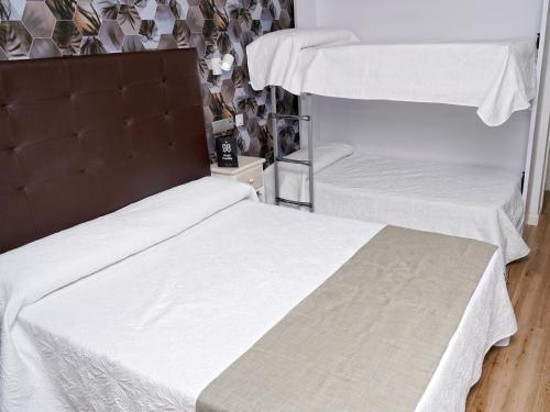 two beds in a room with white sheets at Hotel Castillo Benidorm in Benidorm