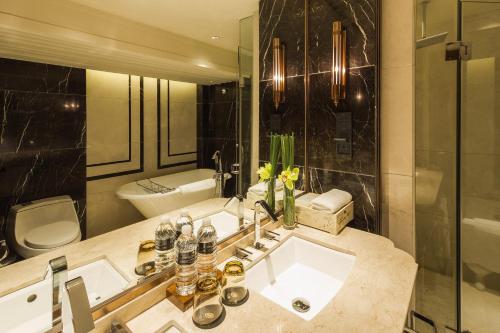 a bathroom with a sink and a toilet and a mirror at InterContinental Shanghai Ruijin by IHG - Downtown Historic Iconic Garden Hotel in Shanghai