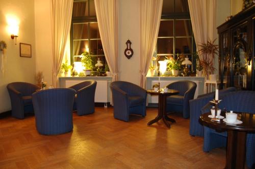 a restaurant with blue chairs and tables and windows at Gutshaus Redewisch Hotel & Restaurant in Boltenhagen
