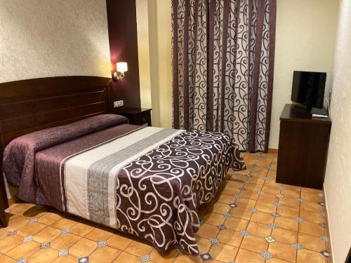 ein Hotelzimmer mit einem Bett und einem TV in der Unterkunft Alcaidia De Magina in Cambil