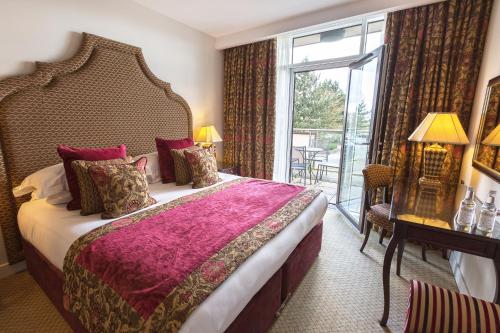 a hotel room with a bed and a large window at The Oxfordshire Golf & Spa Hotel in Thame