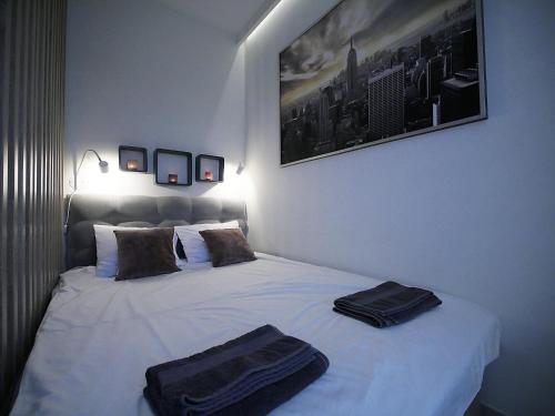 ein Schlafzimmer mit einem weißen Bett mit zwei schwarzen Handtüchern darauf in der Unterkunft 4UApart-Apartment studio Platan New York in Świnoujście