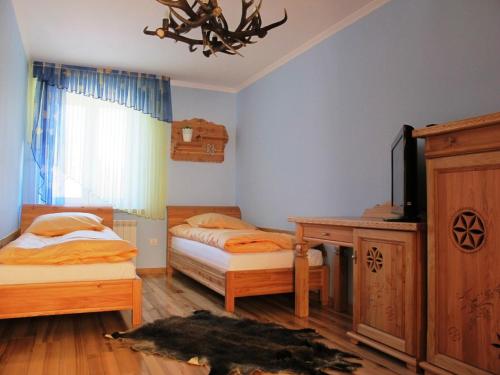 1 dormitorio con 2 camas, escritorio y TV en udanypobyt Apartament Myśliwski, en Kościelisko