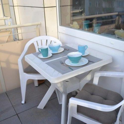 a white table and chairs with bowls and cups on it at Appartement-44 in Westerland