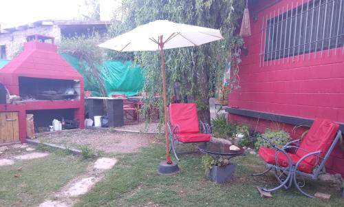 un patio con 2 sillas rojas y una sombrilla en La Bicicleta solar casa abierta en Villa Independencia