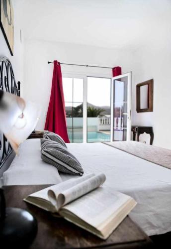 a bedroom with a bed with a book and a window at Villas del Mar. Viña y Cabrera in Puerto Calero