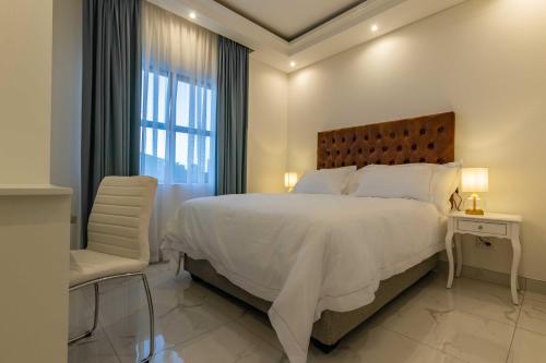 a white bedroom with a large bed and a chair at Oceanway Boutique Hotel/Conference in Cape Town