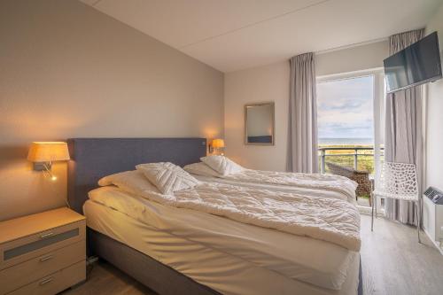 ein Schlafzimmer mit einem großen Bett und einem Fenster in der Unterkunft Appartementencomplex Juliana 116 in De Koog