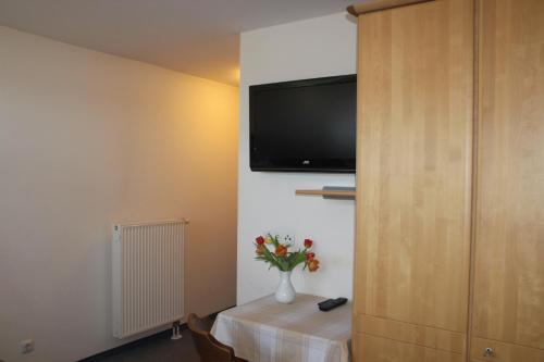 um quarto com uma televisão e um vaso de flores sobre uma mesa em Schwarzer Adler em Schwaighausen