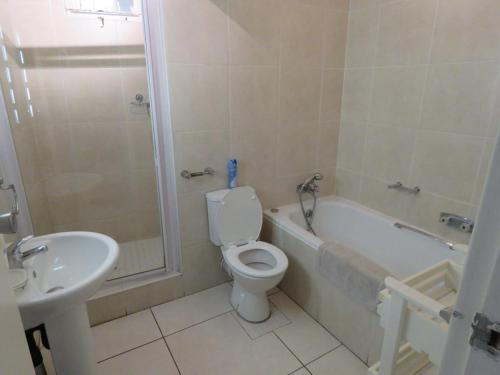 a bathroom with a toilet and a tub and a sink at 130 BREAKERS RESORT HOTEL Umhlanga in Durban