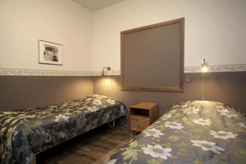 a hotel room with two beds and a mirror at Hotel Himos in Jämsä