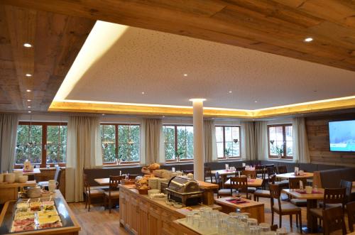 a dining room with tables and chairs and windows at Hotel Starjet in Flachau
