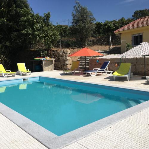 a swimming pool with two lawn chairs and an umbrella at Casa Da Calçada in Castelo de Paiva