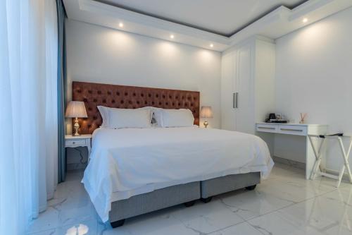 a white bedroom with a large bed and a desk at Oceanway Boutique Hotel/Conference in Cape Town