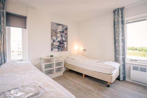 Un dormitorio con dos camas y una ventana. en Appartementencomplex Juliana 132, en De Koog