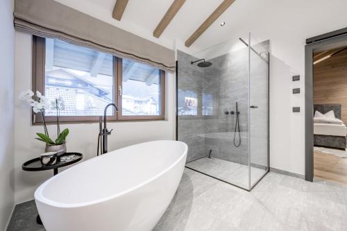 a white bathroom with a tub and a shower at Alpenchalet Tirol in Längenfeld