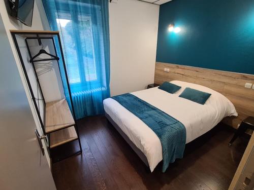 a bedroom with a bed and a blue wall at Berry Hôtel La Châtre in La Châtre