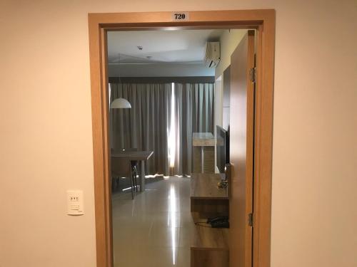 a room with a door leading to a room with a mirror at Flat Park Veredas com Vista Serra com geladeira e fogão in Rio Quente