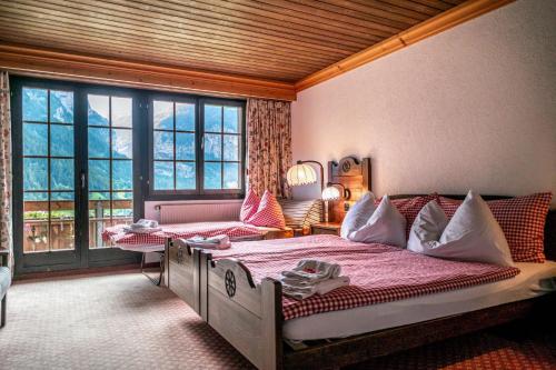 a bedroom with a bed and a large window at Hotel Gletscherblick Grindelwald in Grindelwald