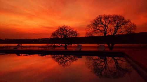 two trees are reflected in the water at sunset at Pousada Recanto do Turvo in Capitólio