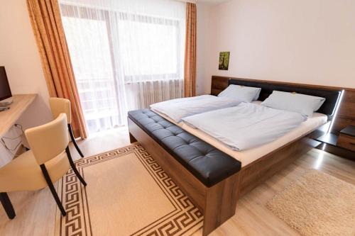a bedroom with a large bed with a black leather seat at Hotel Pension Blüchersruh in Bad Berneck im Fichtelgebirge