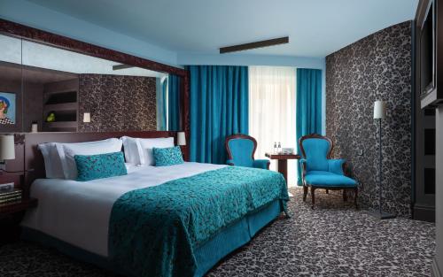 a hotel room with a bed and two blue chairs at Domina St.Petersburg in Saint Petersburg