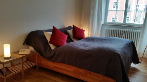 ein Schlafzimmer mit einem Bett mit zwei roten Kissen in der Unterkunft Palais am Schlossplatz in Meersburg