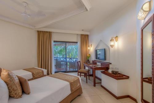 a hotel room with two beds and a desk and a television at Sea Cliff Resort & Spa in Zanzibar City