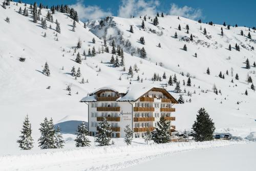 a building in the snow next to a mountain at Apparthotel Sellaronda in Arabba