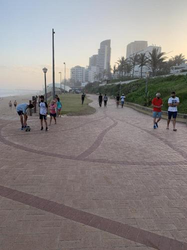 a group of people walking down a brickicked sidewalk at Unit 62 Sealodge Umhlanga Beach in Durban