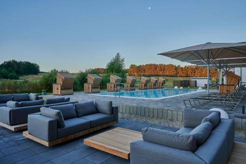 eine Terrasse mit Sofas und einem Pool in der Unterkunft Dorint Resort Baltic Hills Usedom in Korswandt