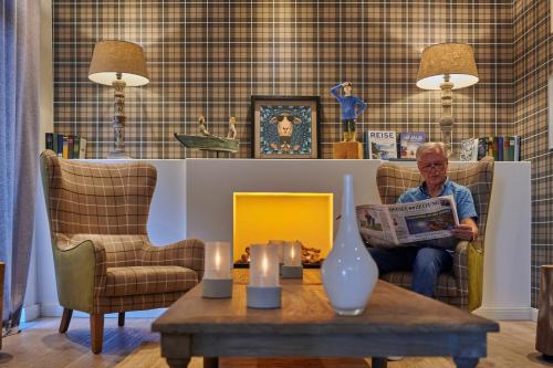 a woman sitting in a chair reading a newspaper at Dorint Resort Baltic Hills Usedom in Korswandt