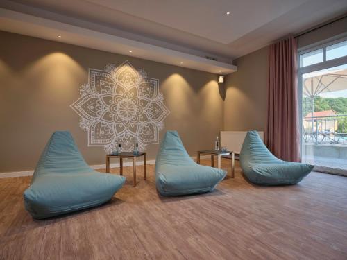 a room with blue chairs and a mandala on the wall at Dorint Resort Baltic Hills Usedom in Korswandt