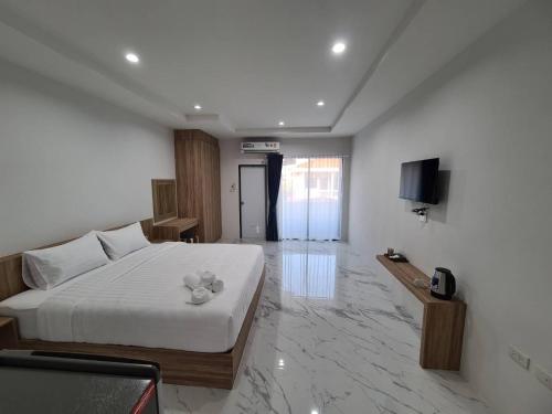 een slaapkamer met een wit bed en een televisie bij Nub Thong Residence in Kalasin