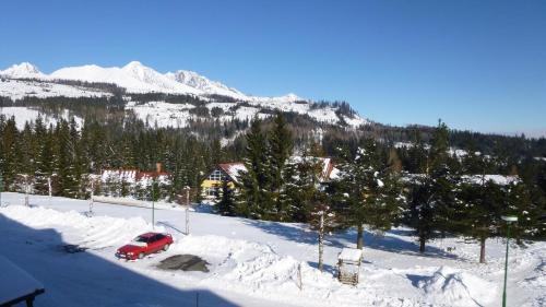 a red truck parked in the snow in front of a mountain at Apartman Glacier in Tatranska Strba