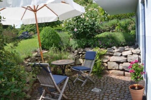 a patio with two chairs and a table with an umbrella at Ferienwohnung Omert in Ehrenberg