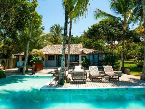 a resort with a pool and chairs and a house at Casarão Alto Mucugê in Arraial d'Ajuda