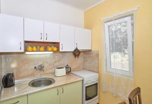 a kitchen with white cabinets and a sink and a window at Green Life - 3 Villas with private Pool in Bryastovets