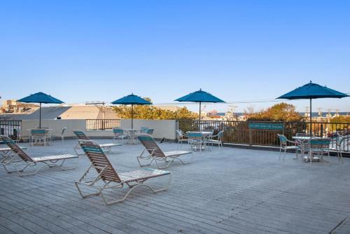 eine Gruppe von Stühlen und Tischen mit Sonnenschirmen auf einer Terrasse in der Unterkunft Brighton Suites Hotel in Rehoboth Beach