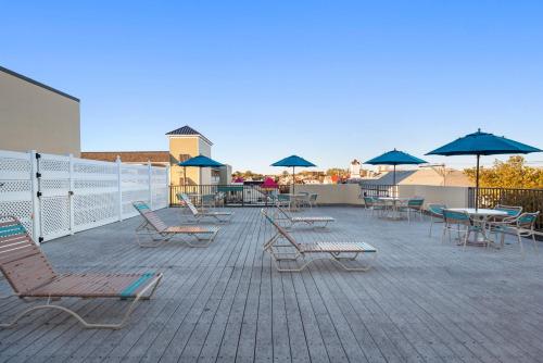 un grupo de sillas, mesas y sombrillas en un patio en Brighton Suites Hotel, en Rehoboth Beach