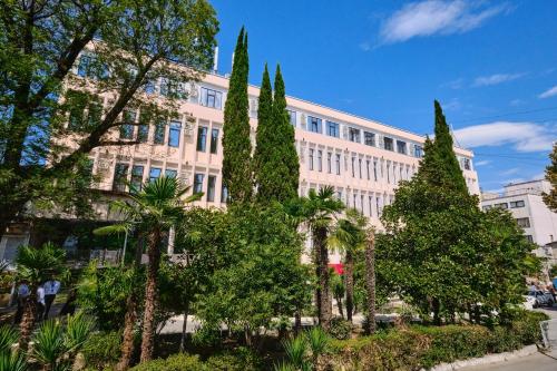 un gran edificio blanco con árboles delante de él en Магеллан Один Сочи, центр en Sochi