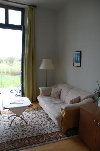 a living room with a couch and a large window at Gutshaus Redewisch Hotel & Restaurant in Boltenhagen
