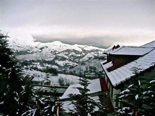 a view of a snowy mountain range with a house at Hotel Rural El Rexacu in Bobia de Arriba