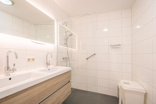 ein weißes Bad mit einem Waschbecken und einem WC in der Unterkunft Appartementencomplex Juliana 154 in De Koog