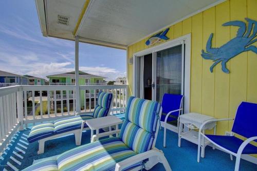 a porch with blue chairs and a table and avisorvisor at The Skipper condo in Holden Beach