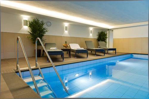 uma piscina com cadeiras e uma mesa ao lado em Wolf Hotel zur Linde em Künzell