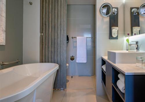 a white bathroom with a tub and a sink at Hyatt Regency Cape Town in Cape Town