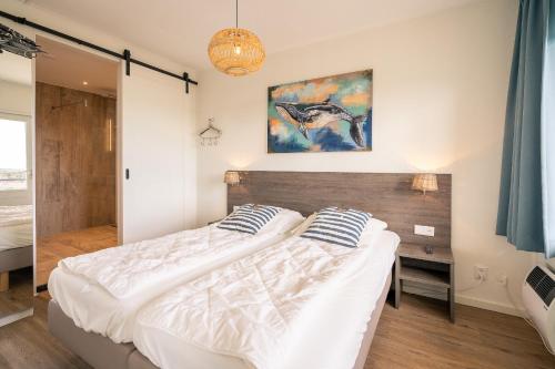 a bedroom with a bed and a painting on the wall at Appartementencomplex Juliana 176 in De Koog