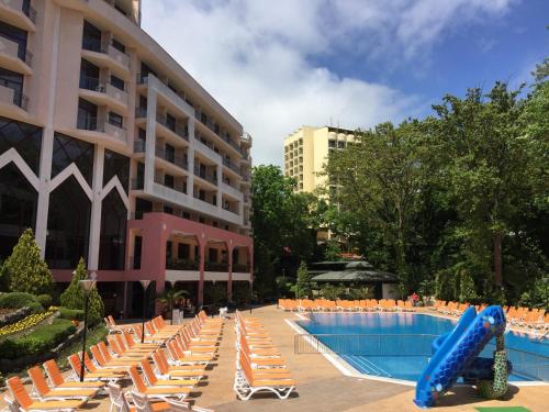 a pool with chairs and a slide in front of a building at Park Hotel Odessos - All Inclusive in Golden Sands