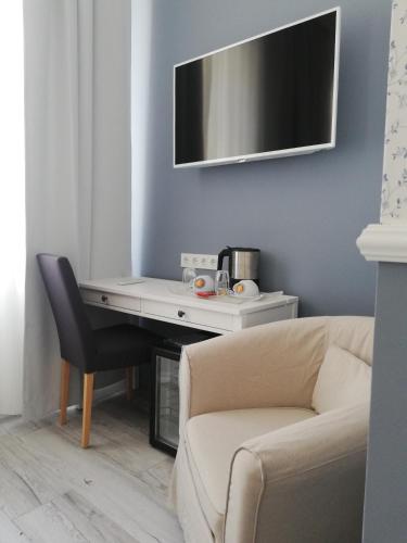 a desk with a couch and a desk with a tv at Boutique Hotel Kugel Wien in Vienna
